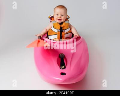 Bambino in kayak rosa con pagaia arancione Foto Stock