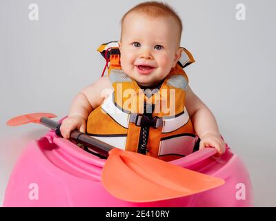 Bambino in kayak rosa con pagaia arancione Foto Stock