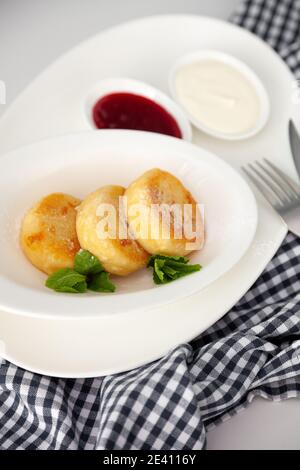 Cheesecake rotondi. Serve piatti fatti in casa su un piatto bianco. Cheesecake con menta per colazione, un servizio di tre persone. Foto Stock