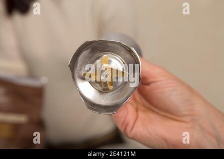 Una mano sostiene un ugello miscelatore con un coltello speciale. Primo piano. Foto Stock