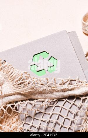 Sacchetti in rete e blocco note riutilizzabile con simbolo di riciclaggio verde su sfondo beige. Zero sprechi e concetto di stile di vita sostenibile. Foto Stock