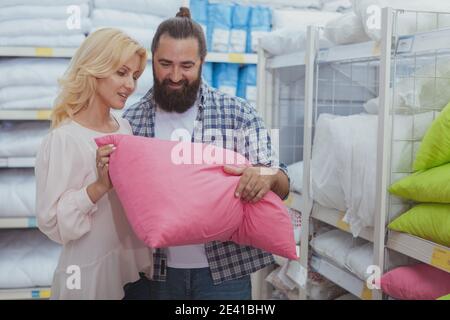 Concetto di sonno sano. Felice coppia matura che sceglie nuovi cuscini per la loro camera da letto, shopping al negozio di mobili. Marito e moglie che acquistano ortopedico p Foto Stock