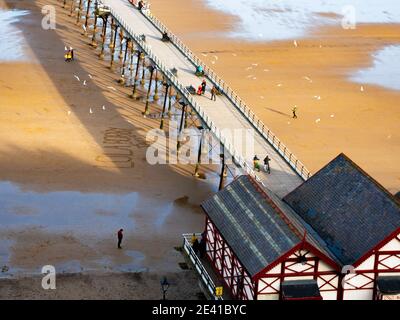 Persone che si esercitano sul molo di Saltburn su un soleggiato durante il pandemia di coronavirus seguendo attentamente il requisito di distanza sociale da mantenere 2 m di distanza Foto Stock