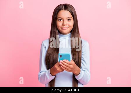 Ritratto di bella ragazza bruno-haired cheery che tiene nelle mani usando gadget isolato su sfondo color pastello rosa Foto Stock