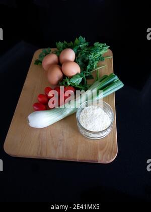 Still Life in luce naturale. Ingredienti omelette su tagliere di legno. Cucina cottura Fotografia. Foto Stock