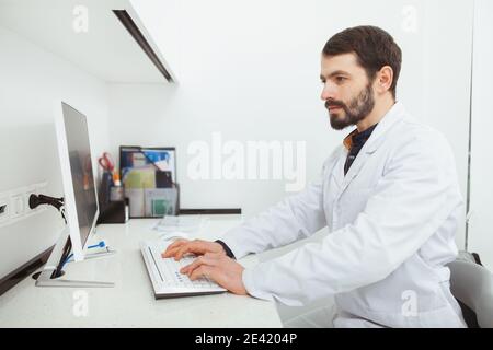 Dentista maturo che lavora al computer nel suo ufficio. Medico di sesso maschile digitando sulla tastiera di un computer, lavorando in ospedale Foto Stock