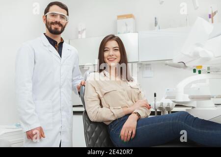 Giovane donna allegra e il suo dentista sorridente alla macchina fotografica dopo esame medico presso la clinica odontoiatrica Foto Stock