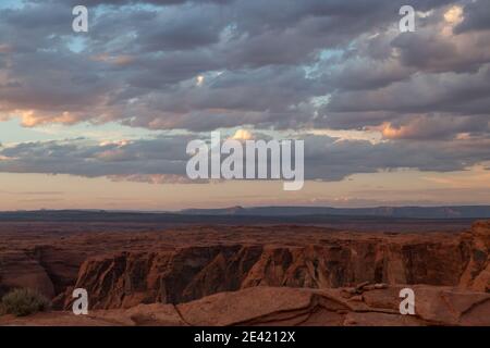 Il sole che tramonta diventa rosa nuvole fluidità basse su Glen Canyons Horseshoe Bend paesaggio nel nord dell'Arizona. Foto Stock