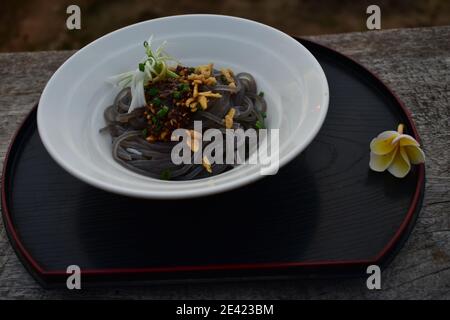 Insalata di noodle di riso nero servita su una ciotola bianca Foto Stock