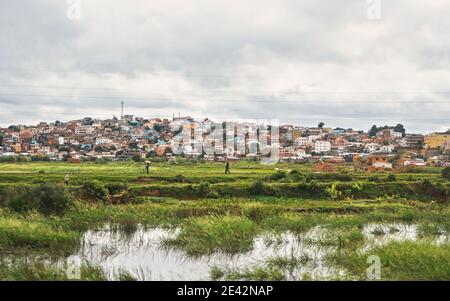 Antananarivo, Madagascar - 24 aprile 2019: Paesaggi tipici durante la giornata di overcast vicino alla capitale del Madagascar, case su piccole colline sullo sfondo, con la gente Foto Stock