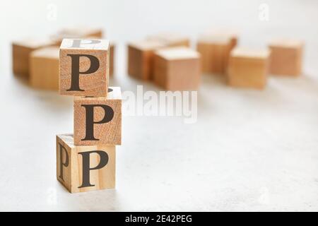 Tre cubetti di legno con lettere PPP (significa lode, immagine, Push), su tavola bianca, più sullo sfondo, spazio per il testo nell'angolo in basso a destra Foto Stock