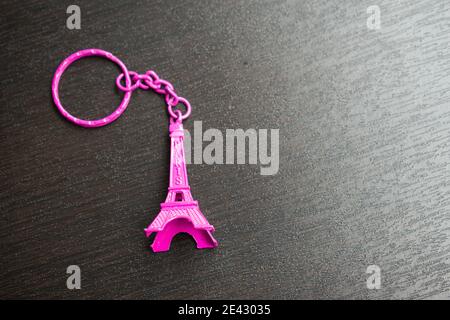 Portachiavi viola della Torre eiffel su un tavolo di legno nero Foto Stock