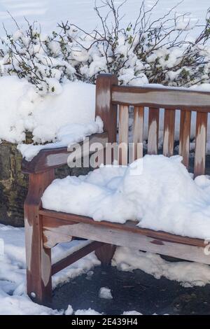 Un sedile da giardino in legno coperto di neve. Foto Stock