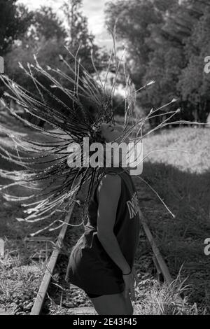 Scala di grigi colpo di una donna ispanica hipster che la flipping wildly capelli stile dreadlock Foto Stock