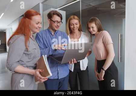 Uomo d'affari esperto che mostra qualcosa sul suo laptop a colleghi di sesso femminile Foto Stock