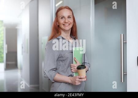 Felice donna d'affari sorridente, con caffè al lavoro Foto Stock