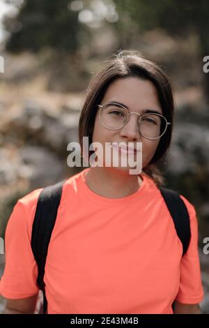 Escursionista femminile che cammina su una strada stretta verso la cima rocciosa della montagna Circondato da una foresta verde durante il viaggio in Spagna Foto Stock