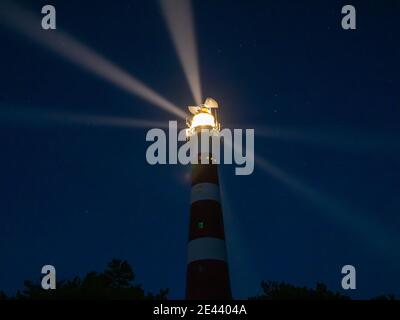Faro con raggi di luce durante la notte, un cielo stellato sull'isola di Ameland, Hollum, Paesi Bassi. Foto Stock