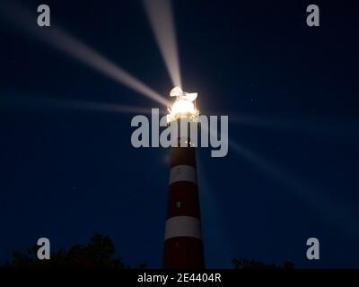 Faro con raggi di luce durante la notte, un cielo stellato sull'isola di Ameland, Hollum, Paesi Bassi Foto Stock
