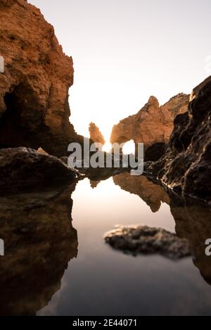 Acque tranquille e pulite della baia situata vicino a ruvidi scogliere contro il cielo di Ponta da Piedade in Algarve, Portogallo Foto Stock