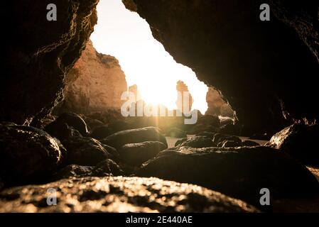 Sabbia rocciosa all'ingresso della grotta vicino al mare nella giornata di sole nelle grotte di Algar seco ad Algarve, Portogallo Foto Stock