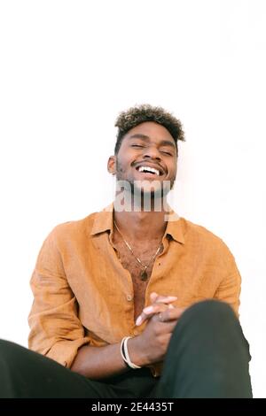 Bel ragazzo nero hipster con i capelli ricci vestito in una camicia bianca casual che guarda la macchina fotografica Foto Stock