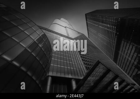 Da sotto l'esterno di edifici alti e moderni con pareti a specchio di vetro sotto il cielo blu scuro sulla strada di Chicago negli Stati Uniti, quadri in bianco e nero Foto Stock