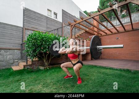 Tranquillo unriconoscibile maschio scalfoot su tappetino e stretching corpo mentre sulla posa verso il basso del cane facendo yoga in città Foto Stock