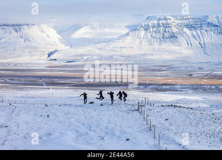 Gruppo di viaggiatori che saltano nella valle innevata mentre si gode l'inverno Avventura in montagna in Islanda e divertirsi Foto Stock