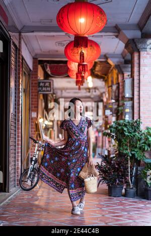 Giovane donna asiatica in abito lungo camminando lungo la storica Daxi Old Street e guardare via mentre si gode la vacanza a Taiwan Foto Stock