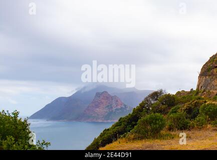 Chapman's Peak- Città del Capo, Sud Africa - 19-01-2021 nuvole che si affacciano su Hout Bay in lontananza. Verde in primo piano. Foto Stock