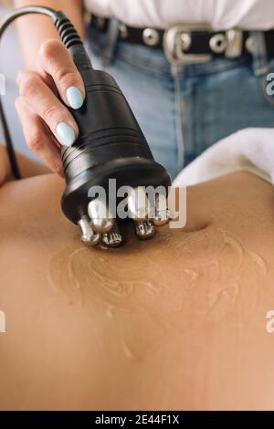 Alto angolo di raccolto irriconoscibile terapeuta femminile utilizzando professionale elettrico strumento durante il massaggio anticellulite per cliente anonimo Foto Stock