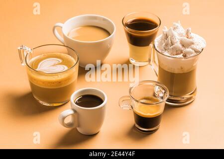 Set ad angolo alto di diversi tipi classici di caffè aromatico bevande servite in tazze di varie dimensioni disposte su beige superficie Foto Stock