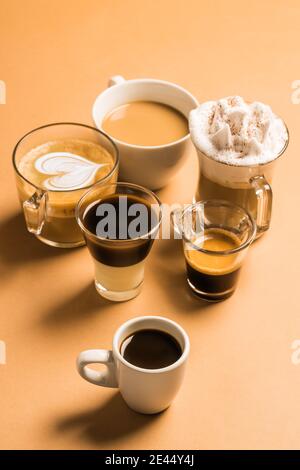 Set ad angolo alto di diversi tipi classici di caffè aromatico bevande servite in tazze di varie dimensioni disposte su beige superficie Foto Stock