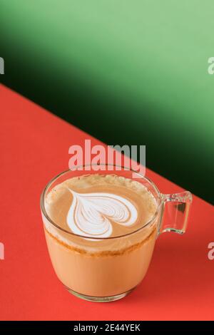Tazza in vetro di cappuccino aromatico fresco e caldo con latte art a forma di cuore servito sul tavolo Foto Stock