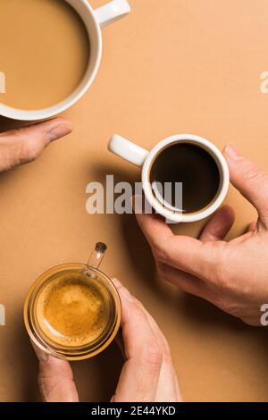 Set di diversi tipi classici di bevande aromatiche al caffè serviti in tazze di varie misure disposte su superficie beige Foto Stock