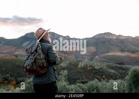Vista posteriore di anziano uomo vagabondatore in piedi su collina e. Ammirate la vista panoramica degli altopiani di Caceres Foto Stock