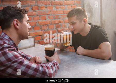 Due amici maschili bevono birra al pub insieme Foto Stock