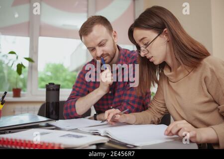 Bella ragazza teenage che fa l'assegnazione con il suo insegnante, copia spazio. Un tutor amichevole che spiega il compito alla sua studentessa adolescente. Brainstorming, idee, le Foto Stock