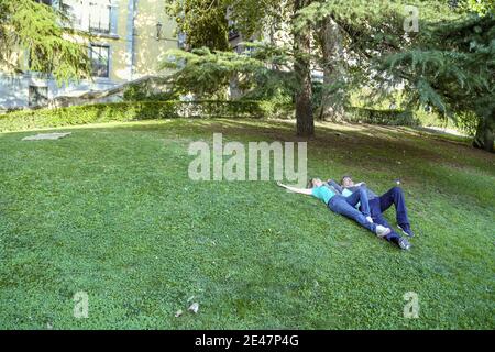 Coppia di mezza età che giace su erba verde su una collina e. rilassante Foto Stock