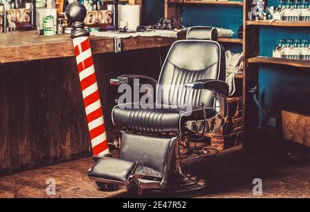 Barbiere palo negozio. Logo del barbiere, simbolo. Elegante sedia barbiere vintage. Acconciature in interni barbiere. Sedia da barbiere. Barbiere Foto Stock