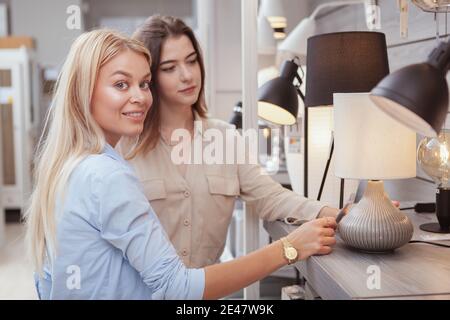 Bella donna felice sorridente alla macchina fotografica, shopping per l'illuminazione domestica con il suo amico. Casalinghe, casa decorazione concetto Foto Stock