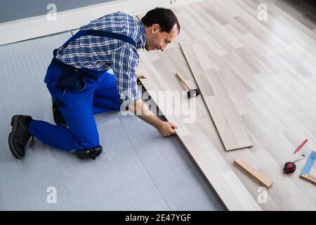 Lavoratore che installa il piano domestico. Carpentiere posa pavimento in laminato Foto Stock