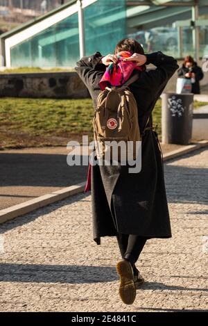 Praga, Repubblica Ceca. 01-21-2021. Donna che cammina nel centro di Praga durante una soleggiata mattina invernale, vicino a un mercato di frutta e verdura. Foto Stock