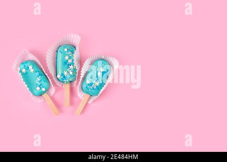 Gelato gustoso e rinfrescante su bastoncini. Gelato alla menta blu su sfondo rosa pastello. Concetto estivo minimo. Disposizione piatta. Foto Stock