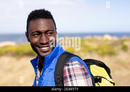 Ritratto di uomo afro-americano indossando zaino escursionismo su costa Foto Stock