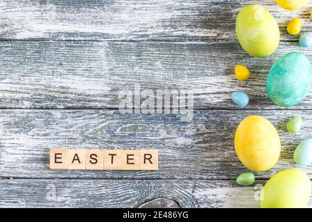 uova di pasqua colorate su sfondo di legno blu shabby e 'pasqua' lettere Foto Stock