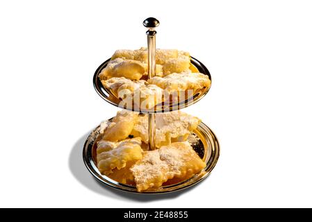 ali di angelo o bugie o frappe o chiacchiere su vassoio a due livelli. Tradizione gastronomica italiana di carnevale. Isolato su sfondo bianco Foto Stock