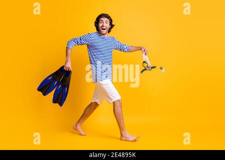 Foto laterale profilo a dimensione intera di Guy Hold scuba diving le alette degli ingranaggi della maschera vanno indossate corti blu bianco isolati sopra sfondo di colore giallo Foto Stock