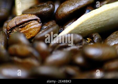 Macro primo piano di alcuni fagioli di caffè arrosto in e. Intorno ad una piccola sessola di legno Foto Stock